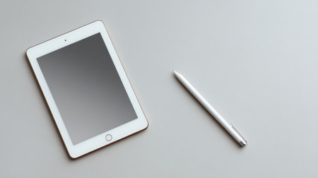A modern tablet paired with a sleek stylus rests on a minimalist gray surface, perfect for showcasing technology, creativity, and digital productivity themes in stock photography.の素材