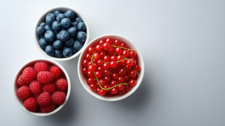 A stunning display of fresh berries in white bowls, featuring blueberries, raspberries, and red currants, ideal for healthy meals, desserts, or vibrant culinary presentations.の素材