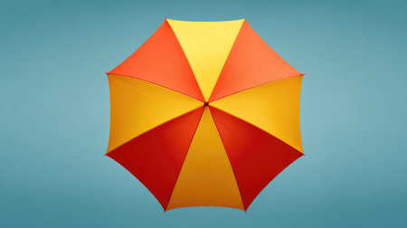 Bright and colorful umbrella features a playful design with red and yellow panels, set against a serene blue background, perfect for summer-themed projects.の素材