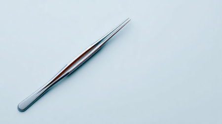 One pair of laboratory forceps placed diagonally across a clean white surface with copy spaceの素材