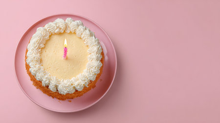 A beautiful round cake with cream frosting and a pink candle sits on a pink plate, ideal for birthday celebrations or as a delightful dessert in various food contexts.の素材