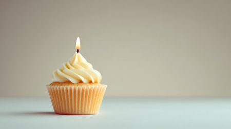 A beautifully crafted vanilla cupcake topped with creamy frosting and a lit candle, ideal for birthdays and celebrations, creating a warm and inviting atmosphere.の素材