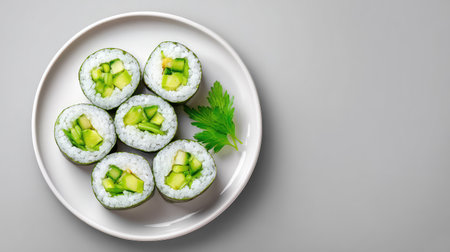 This image showcases a plate of freshly prepared sushi rolls filled with creamy avocado and crisp cucumber, beautifully arranged on a minimalist gray surface.の素材