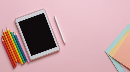 A modern workspace features a tablet alongside colorful pencils and pastel sheets on a soft pink background, ideal for inspiring creativity and enhancing productivity in artistic endeavors.の素材