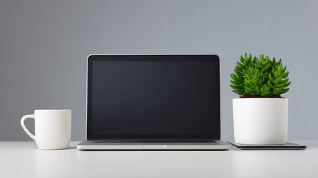A sleek laptop, white coffee cup, and lush green plant define a serene workspace, promoting creativity and comfort in a modern, minimalist setting perfect for productivity.の素材