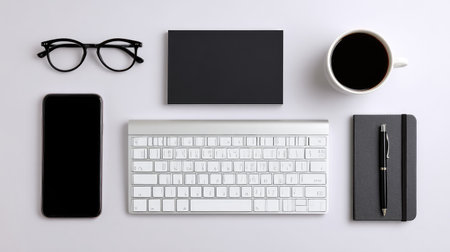 A clean and minimalist desk setup featuring a keyboard, smartphone, glasses, coffee mug, notebook, and pen, ideal for creating a productive workspace in neutral colors.の素材