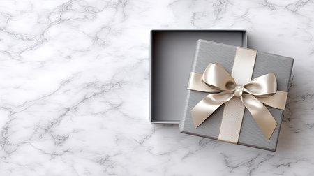 An elegant gray gift box adorned with a satin ribbon, resting on a luxurious marble background. Perfect for showcasing celebratory moments and special occasions.の素材