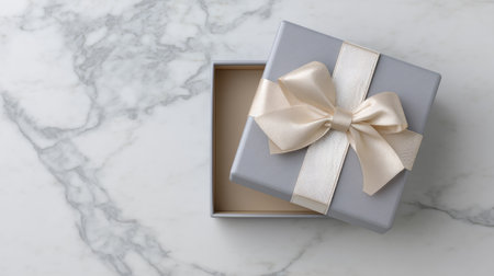 An elegant gray gift box adorned with a cream-colored bow rests on a beautiful marble surface, ideal for adding a touch of sophistication to celebrations.の素材