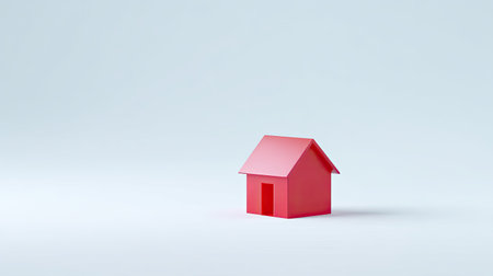 A vibrant red miniature house model set against a soft gray background, ideal for concepts related to real estate, home ownership, and design.の素材