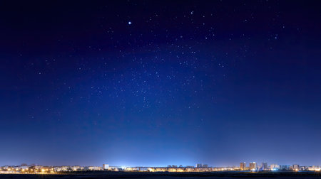 A mesmerizing night sky filled with twinkling stars stretches over an urban landscape, showcasing the beauty of city lights beneath a tranquil blue atmosphere, offering a serene escape into the night.の素材