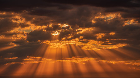 This stunning sunset scene features dramatic clouds illuminated by radiant rays of light, creating a breathtaking display of orange and yellow hues in the sky.の素材
