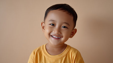 A charming portrait of a young boy with a joyful smile, dressed in a yellow shirt. Perfect for capturing the essence of childhood happiness and innocence.の素材