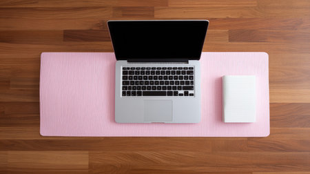 A serene workspace scene featuring a laptop on a pink yoga mat alongside a white notebook. Perfect for illustrating productivity and wellness in a calming environment.の素材