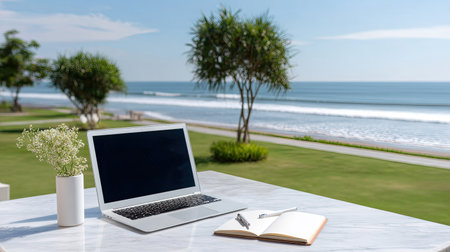 A beautiful outdoor workspace featuring a laptop, notebook, and pen, set against a stunning beachfront view, inviting creativity and relaxation in nature.の素材