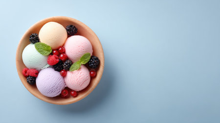A vibrant arrangement of colorful ice cream scoops nestled in a bowl, accompanied by fresh berries and mint leaves, creating a visually appealing summertime dessert.の素材
