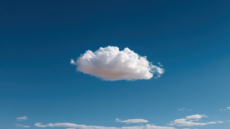 A solitary fluffy cloud drifts across a bright blue sky, embodying tranquility and natural beauty. The scene captures the essence of clear weather and calmness.の素材