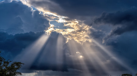 A stunning display of nature featuring dark clouds illuminated by radiant sunbeams breaking through, creating a breathtaking atmospheric scene filled with wonder.の素材