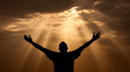 A striking silhouette of a person with raised arms explores themes of freedom and spirituality, framed by a stunning display of light breaking through clouds.の素材