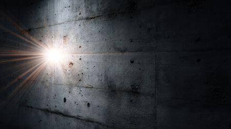 A powerful light burst pierces a dark concrete wall, creating dramatic contrasts and shadows that evoke a sense of mystery and solitude in the space.の素材