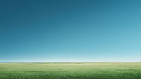 A pristine view of expansive green grassland stretching under a clear blue sky. Ideal for nature themes, backgrounds, or peaceful settings.の素材