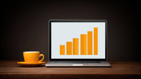 A sleek laptop showcases a growth chart with vibrant orange bars, paired with a stylish coffee cup, highlighting a modern workspace focused on productivity and business success.の素材