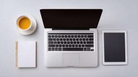 A neat and organized workspace featuring a laptop, tablet, and notebook alongside a cup of coffee, perfect for enhancing focus and creativity in remote work settings.の素材