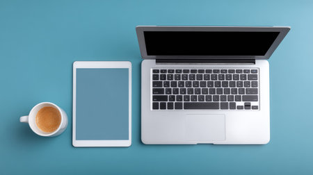 A modern workspace featuring a laptop and tablet on a vibrant blue surface, complemented by a cup of coffee, ideal for remote work and creative projects.の素材