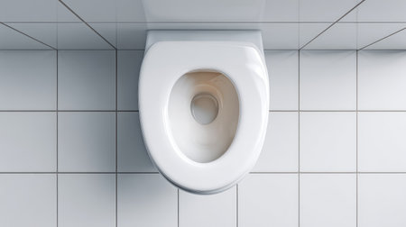 Overhead view of a clean white porcelain toilet in a modern bathroom setting, showcasing a minimalist design with bright tiles, ideal for home interior inspiration.の素材