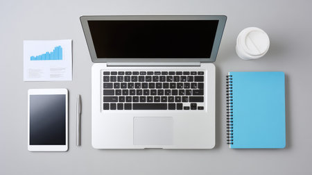 A visually appealing workspace with essential tools for productivity, featuring a laptop, tablet, notebook, pen, and coffee cup, ideal for creative professionals.の素材