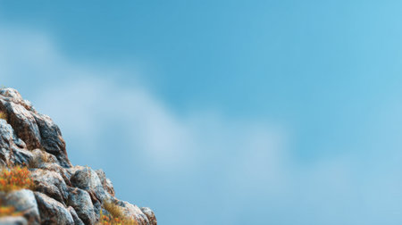 This image captures a rocky mountain landscape under a bright blue sky. Soft clouds add depth, creating a peaceful and serene outdoor atmosphere ideal for nature lovers.の素材
