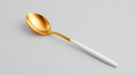 This image showcases an elegant gold spoon with a white handle, perfect for modern kitchen decor or culinary presentations. Ideal for gourmet and dining themes.の素材