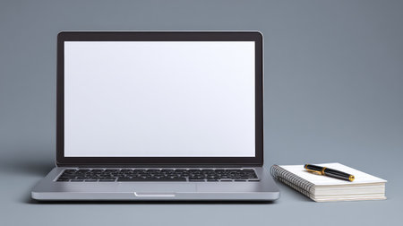 A sleek laptop with a blank screen is positioned next to an elegant notepad and pen, showcasing a modern workspace perfect for creativity and productivity.の素材