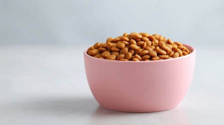 Close-up of brown roasted nuts served in a pink bowl, perfect for healthy snacking or culinary use, with appealing texture and color on a light, minimalistic surface.の素材