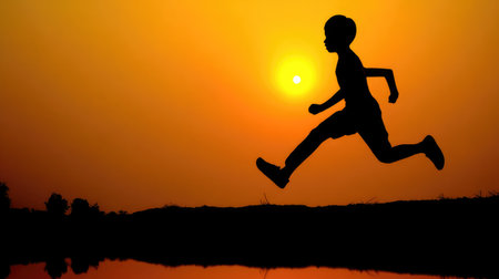 A captivating silhouette of a young boy joyfully running against the backdrop of a stunning sunset, capturing the essence of childhood energy and freedom in a peaceful landscape.の素材