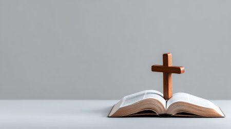 An open Bible with a wooden cross on top, representing faith and spirituality in a minimalistic composition, perfect for showcasing religious themes and inspiration.の素材