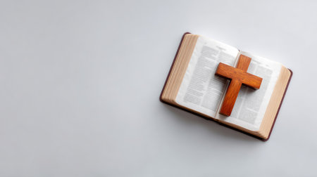 A serene image of an open Bible with a wooden cross, perfect for illustrating themes of faith, spirituality, and devotion in various religious contexts.の素材
