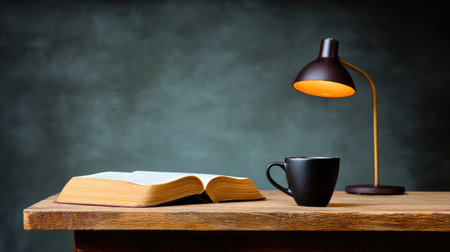 A serene and inviting scene featuring an open book, a coffee cup, and a stylish lamp on a wooden desk, perfect for cozy reading moments or study sessions.の素材