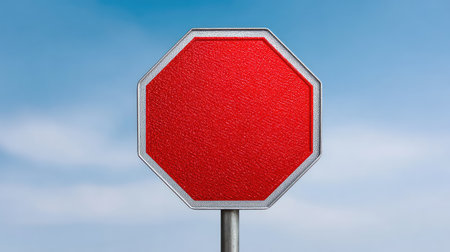 A vivid red stop sign stands alone against a clear blue sky, representing the essential theme of traffic regulation and safety in urban landscapes.の素材