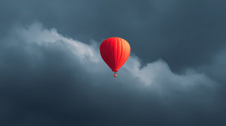A striking hot air balloon in brilliant orange floats gracefully amidst dark clouds, symbolizing freedom and adventure in the vast sky, perfect for travel and leisure themes.の素材