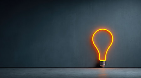 A bright neon light bulb casts a warm glow against a minimalist gray wall. This image symbolizes creativity and innovation, ideal for artistic projects or modern design themes.の素材