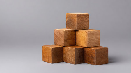 A visually striking arrangement of wooden cubes in a pyramid shape, perfect for concepts related to creativity, design, and educational play on a smooth gray background.の素材