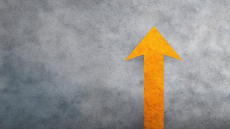 A dynamic orange arrow stands out against a textured gray background, perfect for illustrating direction, motivation, and progress in various design projects.の素材