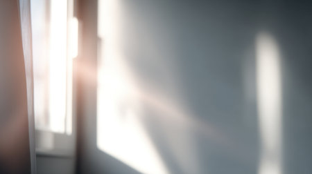 Soft sunlight filters through a window, creating beautiful shadows and a warm atmosphere in a minimalist interior, evoking feelings of calm and tranquility.の素材