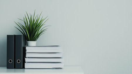 A minimalist office with a clean desk, neatly stacked papers, and a plant in the corner, offering space for business organizational messaging.の素材