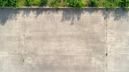 Aerial view of an old concrete sidewalk with visible cracks, worn edges, and natural surface aging.の素材