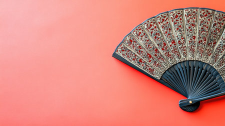 A decorative fan with intricate Chinese designs, set against a bright red background with ample copy space.の素材