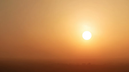 A breathtaking view of a golden sunset illuminating a misty landscape, offering calm and tranquility. Perfect for nature lovers and photography enthusiasts seeking serene scenery.の素材