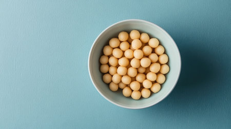 A minimalist shot of cheese balls in a plain white bowl, set on a blue textured surface.の素材