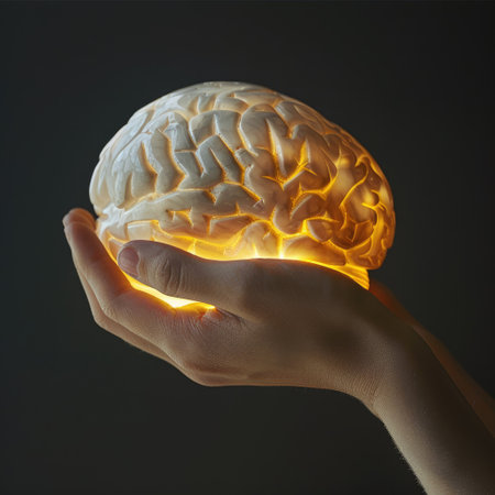 Symbolic image of a hand gently holding an illuminated human brain sculpture, depicting the concept of intelligence and creativityの素材