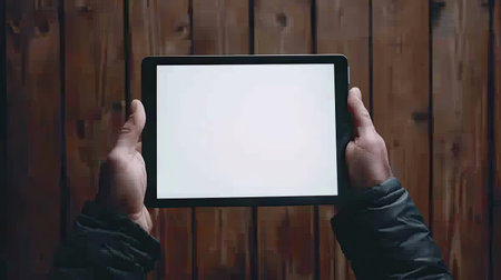 Hands gripping a tablet with a white screen, ready for input or designの素材